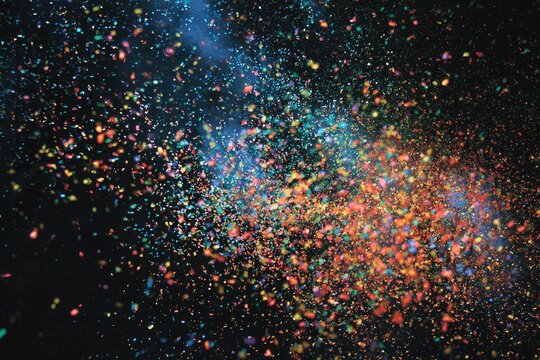 Vibrant, colorful particles explode outwards against a dark background