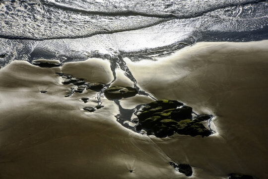 Beach with rocks exposed by the tide.
Low tide on a beach at sunset.