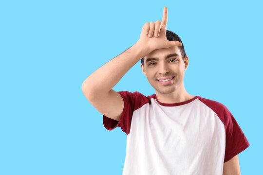 Young man showing loser gesture on blue background