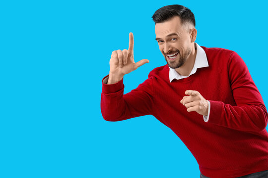 Handsome man showing loser gesture on blue background