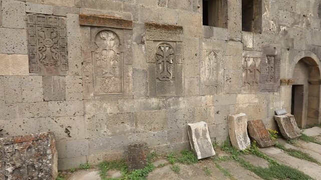  A slow pan reveals a historic stone wall adorned with intricately carved ancient Armenian khachkars. These beautiful stone crosses are a testament to rich cultural and religious heritage.