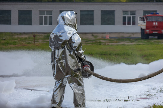Firefighters use a foam generator to supply foam to extinguish the fire. Firefighters in protective clothing against high temperatures in a fire. Firefighters in shiny suits with foam generators.