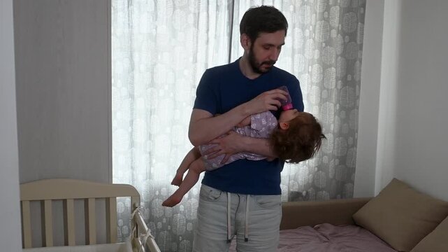 Young father and toddler daughter morning bonding during bottle feeding. Warm family connection moment showing strong father-daughter relationship during everyday home life
