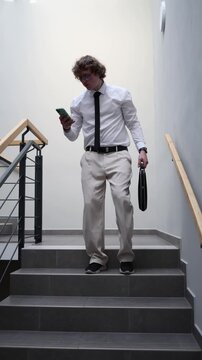 Vertical screen office worker walks down stairs looking at phone surprised by small salary after long workday feeling disappointment stress and frustration about low income and effort mismatch