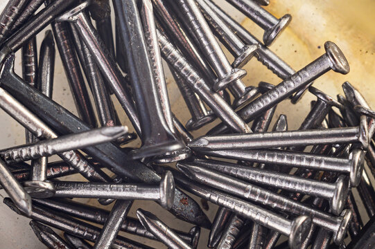 Close-up macro shot of a pile of metal nails with sharp points and textured shafts
