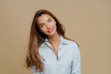 Fototapeta premium Smiling young woman portrait on beige studio background