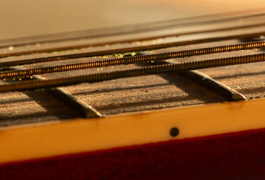 Detailed shot of a vintage guitar fretboard with bronze frets and oxidized strings, telling the story of melodies played over years