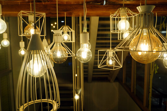 Group of decorative industrial pendant lights with glowing Edison bulbs, stylish modern interior lighting for cafe and home decor.