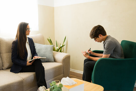 Teenager performing cognitive behavioral therapy exercises with a psychologist during a counseling session