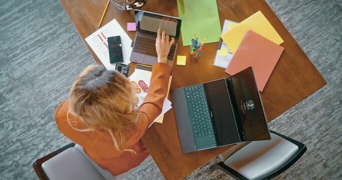 Busy Woman Working at Desk with Laptops and Documents
