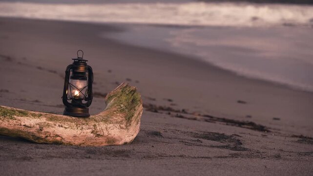 夕暮れの砂浜に置かれたアンティークなハリケーンランタン

