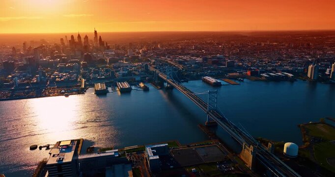 Stunning orange sky over Philadelphia, Pennsylvania, USA at sunset. Distancing from the Delaware River with the Benjamin Franklin Bridge across it.