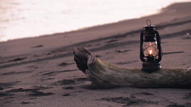 夕暮れの砂浜に置かれたアンティークなハリケーンランタン
