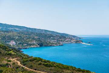 Fototapeta premium Evdilos, Ikaria Greek fishing island Aegean village cityscape with houses homes by coast of Icarian sea harbor marina pier with boats