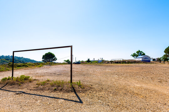Soccer football dirt dry field with gate at Perdiki mountain village on Ikaria island, Greece rural countryside small town at longevity blue zone