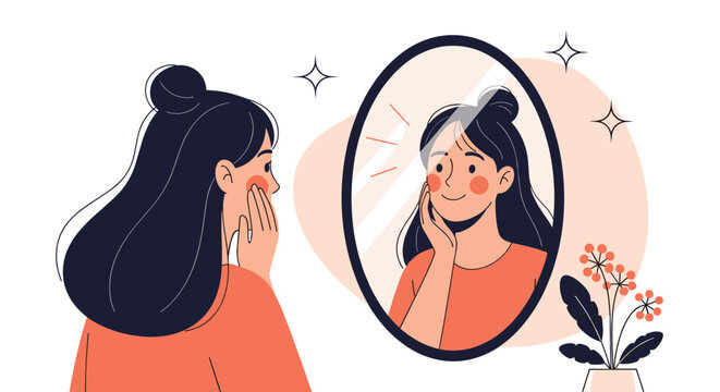 Contented young woman smiling and touching her face while looking at her reflection in a large oval bedroom mirror.
