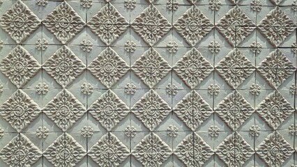Traditional Thai floral relief pattern on yellow sandstone wall, architectural exterior texture of decorative terra cotta tiles, oriental heritage background. © Tatah87