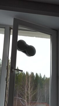 A Hand Using a Remote Control to Operate a Window with Balloons Attached, Showcasing Innovative Use of Technology in Home Automation