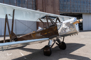 Vintage silver-brown biplane aircraft parked near hangar © ZenitX