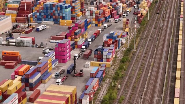Santo Stefano di Magra, Italy - 18 April 2026: Aerial view of Retroporto merci with stacks of colorful shipping containers, trucks moving through the yard, and railway tracks.