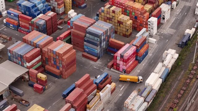 Santo Stefano di Magra, Italy - 18 April 2026: Aerial view of the Retroporto merci freight terminal with stacked colorful shipping containers, trucks, and railway tracks in Liguria.