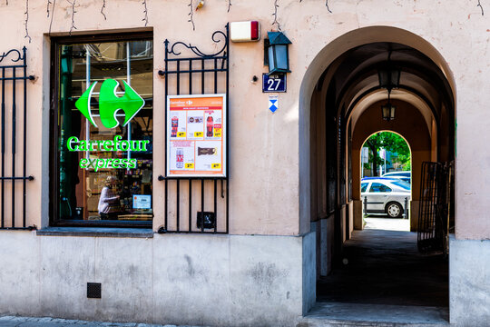 Warsaw, Poland - April 23, 2025: Old town street with closeup of Carrefour express convenience grocery store shop sign in historic nowe miasto