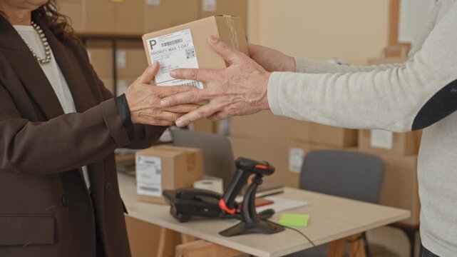 Woman handing small parcel with visible hands at a packing table in warehouse; trust small business.