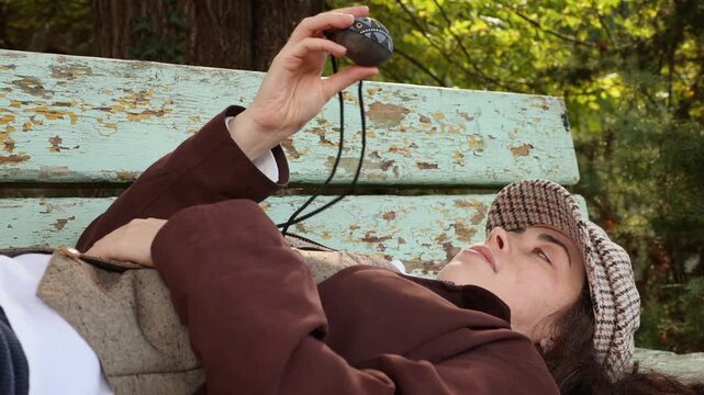 Mid shot of woman looking at an upturned clay whistle of ocarina, lying on bench. Ethnic music on a whistle toy