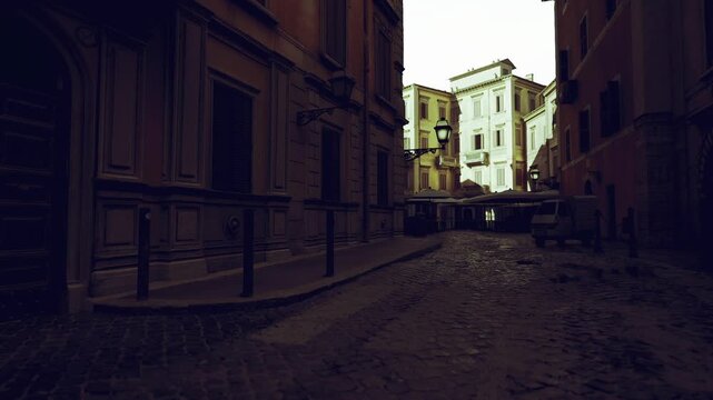 Wet narrow street at dawn, closed cafe awnings, shallow puddles reflecting pale sky, stone facades, muted color palette, quiet premarket atmosphere