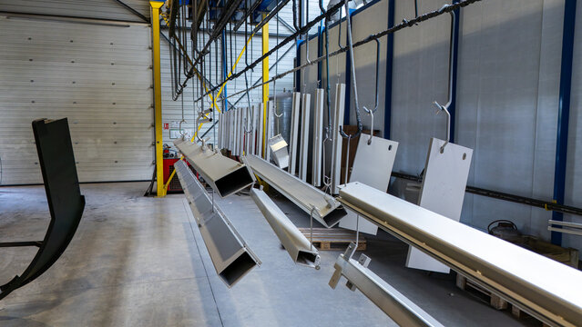 Alignement de profil&eacute;s et plaques m&eacute;talliques suspendus sur une ligne de production pour le traitement de surface en milieu industriel.