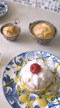 Cinematic Video Presentation of Artisanal Dessert. Professional edit captures final plating of homemade lemon bundt cake with fresh raspberries and citrus zest. Smooth camera movements highlight