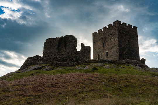 Dolwyddelan Castle keep and crumbling curtain walls on a rocky hilltop beneath a brooding morning sky