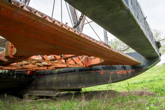Wide suction head with drag shoe and dual intake pipes on vintage  river dredge in dry dock
