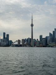Fototapeta premium Toronto, Ontario, Canada, June 13, 2025: Toronto Skyline and Lake Ontario from ferry boat. The CN Tower and Rogers Center in Downtown Toronto are viewed from Lake Ontario.