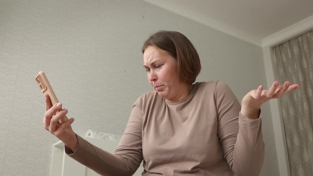 Mid shot of young adult Caucasian woman emotionally angry talking on a smartphone. Bottom view. The concept of modern communication and social media