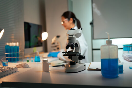 Scientist conducting research experiment visualizing cells using microscope