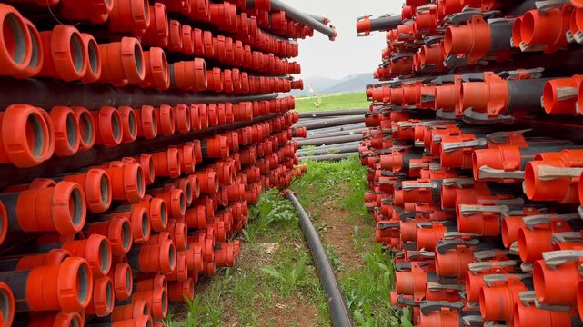 Stacked orange pipes. agricultural new pipes for watering fields, stacked on the grassHigh quality 4k footage