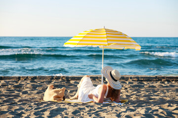 Woman relaxing under beach umbrella looking at the sea © dragonstock