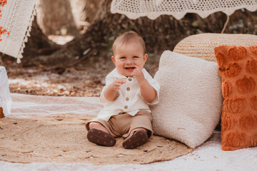 Fototapeta premium Happy mother and toddler son enjoying a bohemian autumn picnic in an outdoor park with pumpkins and fall decor
