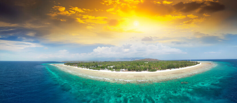 Stunning overhead shot of Gili Trawangan coastline under clear blue sky with crystal clear ocean, coral reefs, and tropical island landscape