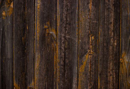 Vintage dark wooden planks texture. Weathered wood background with yellow paint remains.