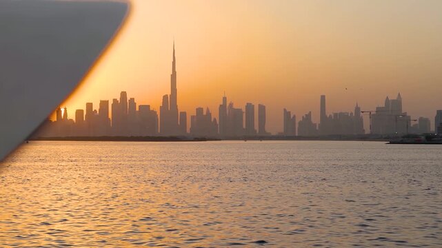 Establishing view of a elegant woman with hat looking at the skyline of Dubai, UAE, during a beautiful sunset