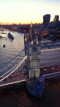Establishing aerial view of the famous Tower Bridge and the illuminated skyline of London, England, during dusk