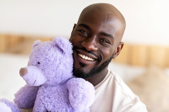 Man holding purple stuffed bear and smiling in bright bedroom