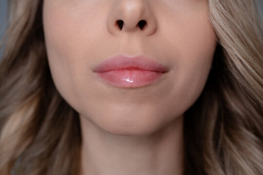 Close up of young woman with natural lips after permanent makeup procedure. Soft pink tint, defined contour and smooth hydrated skin. Beauty treatment and long lasting lip enhancement concept