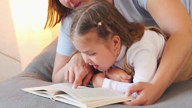 Bedtime reading session between a caregiver and a child. Preschool education and language development. Close up
