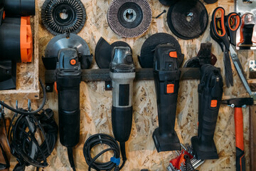 Tool storage. Workshop wall set. Electric angle grinder discs hanging on metal rack with professional handheld power equipment in carpentry. © golubovy