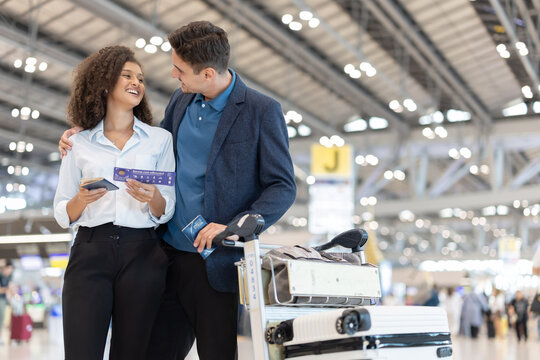Couple checks travel details on their ticket at the airport before their flight