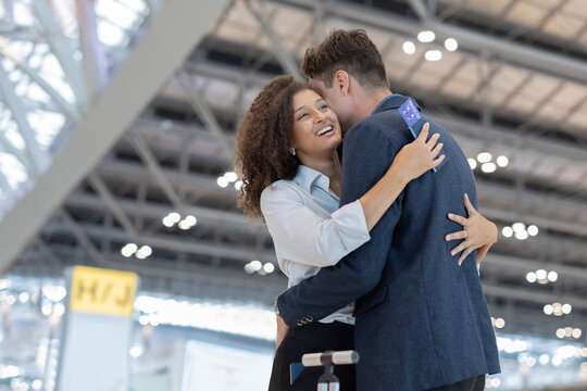 A man and woman embrace warmly in the airport