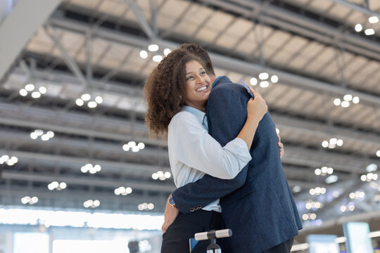A man and woman embrace warmly in the airport